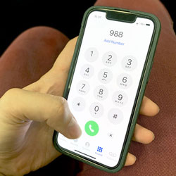 A person holding a phone in their hand set to dial the new suicide hotline, 988.