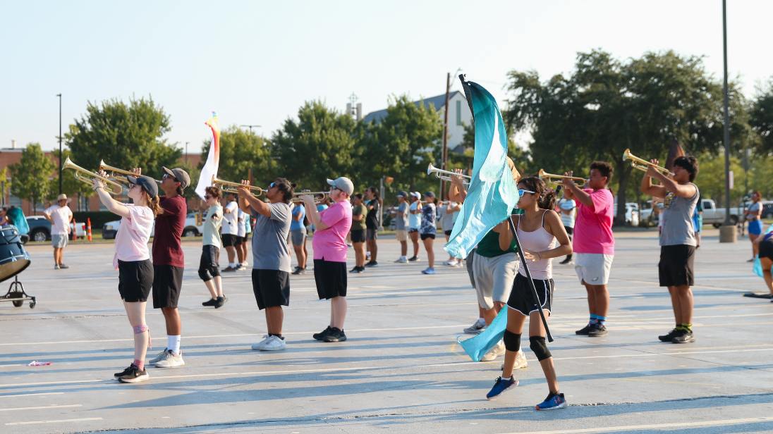 students stand with instruments and color guard flags