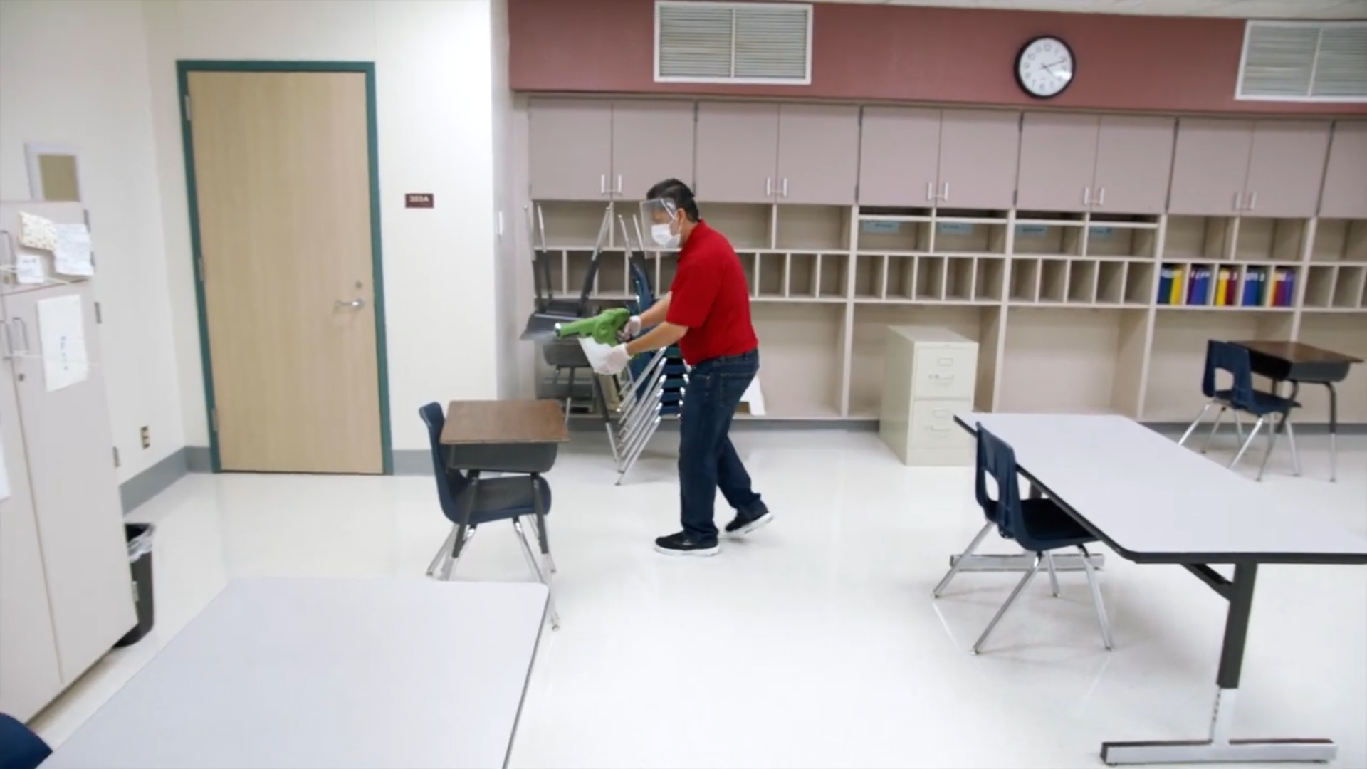 Custodian sprays disinfectant in classroom