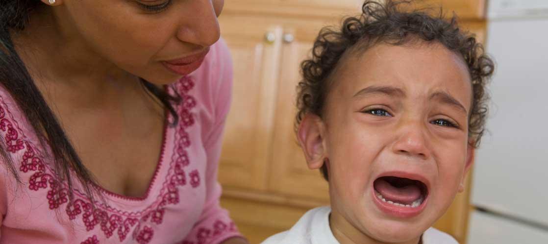 parent looking over close up of toddler boy crying