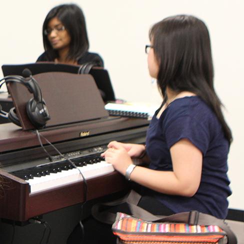 Two girls playing pianos in the classical magnet class