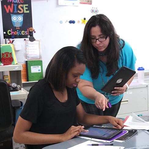 A teacher helping a student on an iPad