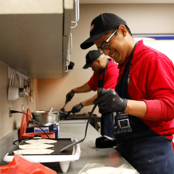 A smiling MACS student preparing tortillas