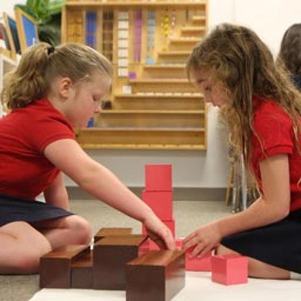 Two girls in Montessori working on an assignment using blocks