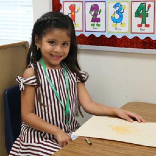 Pre-K girl coloring at a desk