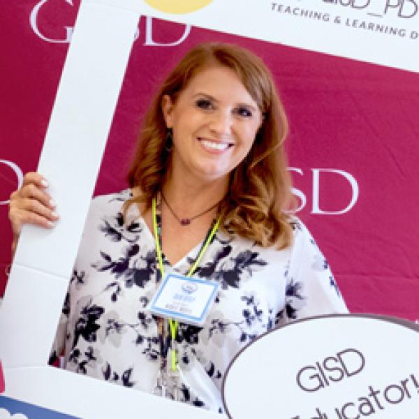 A beginning teacher posing for a photo at New Teacher Orientation.