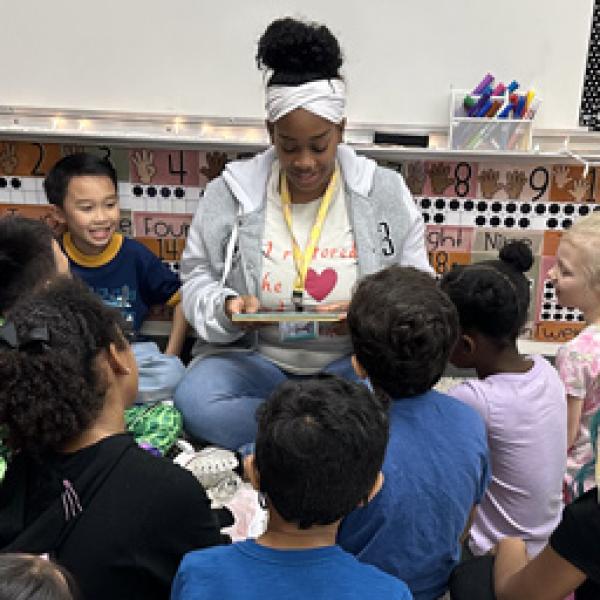 A teacher sitting with her students for a reading circle.