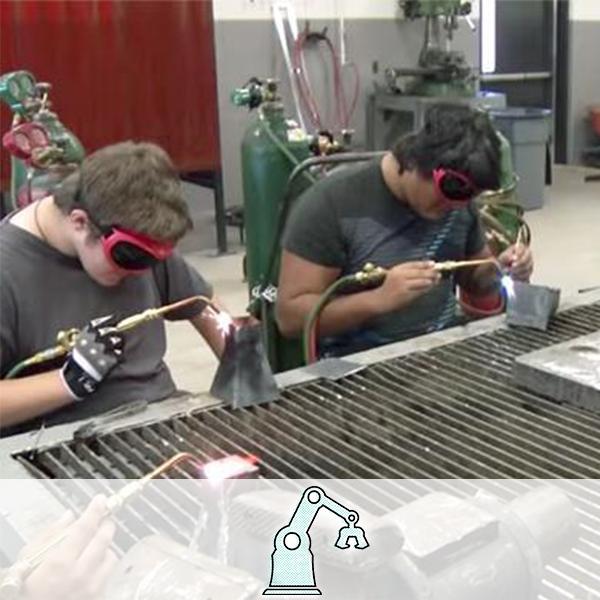 Students welding metal at a grate table. A robotic arm icon is overlaid on the image, representing the Manufacturing cluster.