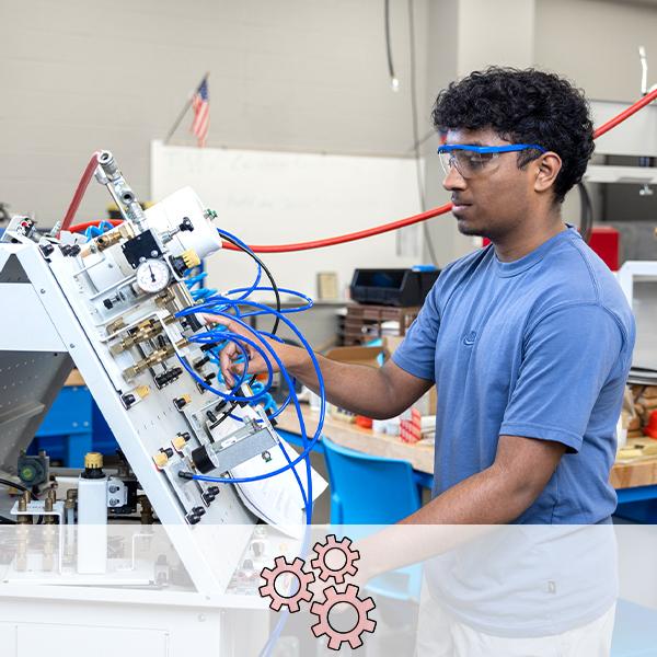 A student in safety glasses works on a pressurized pump board, wires going everywhere. An icon of three gears is overlaid.