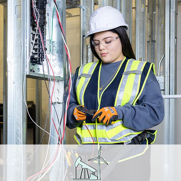 A girl works on cutting electrical wires inside a housing frame, wearing full protective gear. An icon of an oil pump jack and a wind turbine are overlaid.