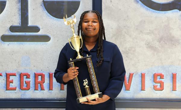 Casey Dozier smiles while holding her InvestWrite trophy.
