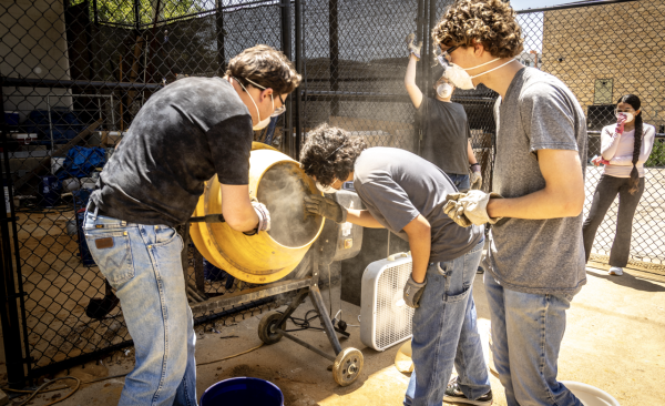 A group of male students look into a cement mixer as it turns