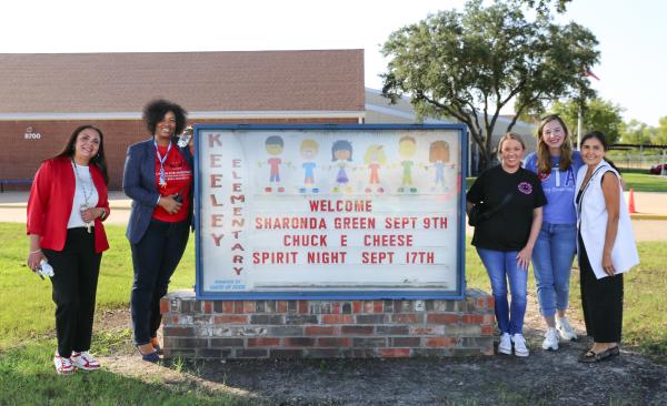 A group of five women stand in front of the Keeley Elementary marquee sign