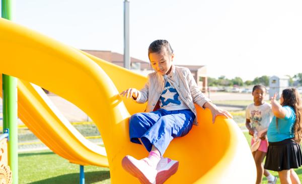 Young girl smiles while going down a slide