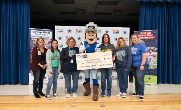 Dallas Cowboys mascot poses with a group of teachers, holding a large check