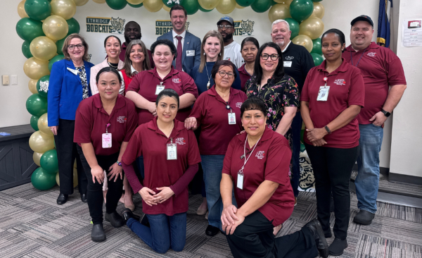 A diverse group of adults stand in front of a backdrop