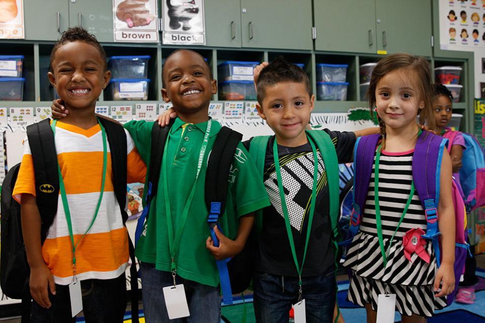 4 young students, three boys and a girl, wearing dress code appropriate clothing.