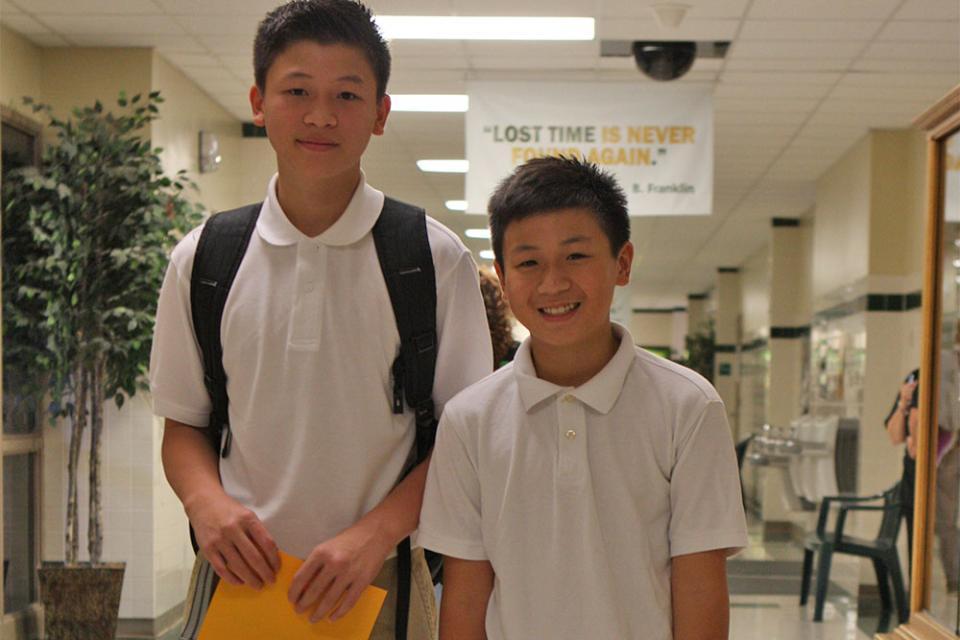 Two middle school boys wearing white polo-style shirts compliant with standardized dress.