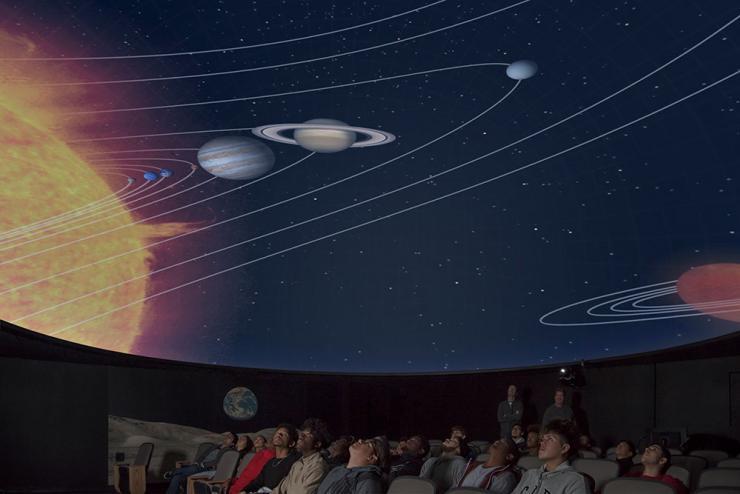 Students look up at dome screen displaying image of the solar system.