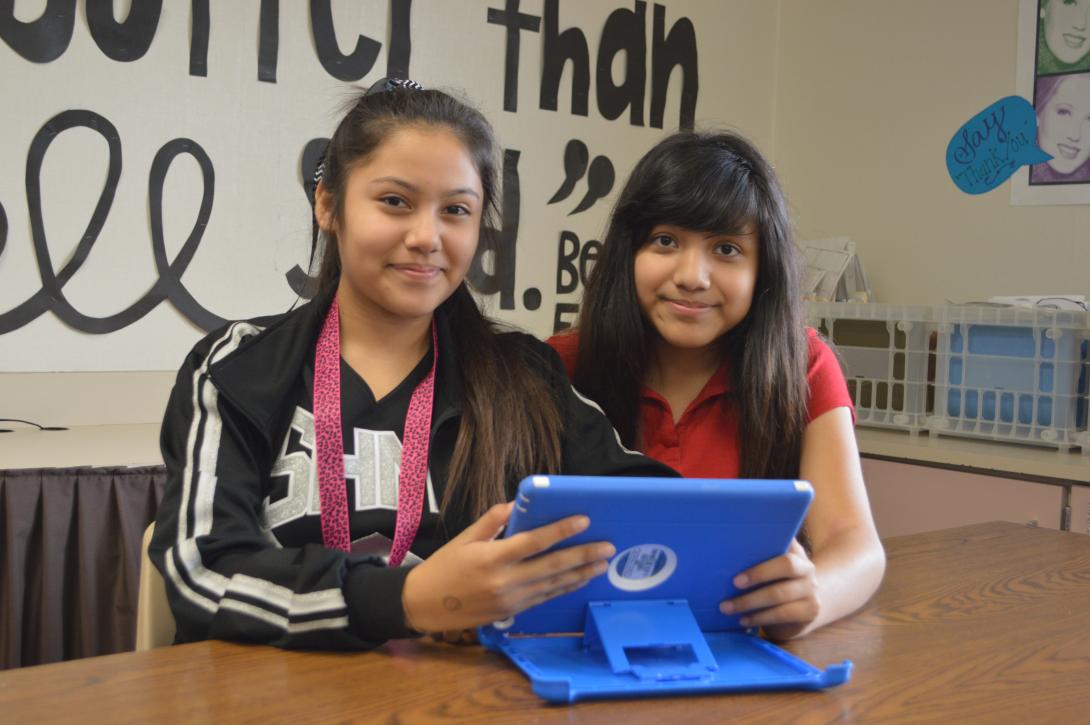 Two girls using an iPad to read in class