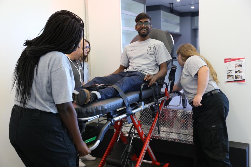 Students practicing loading people into an ambulance