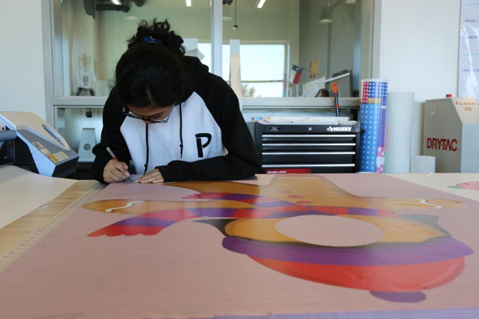 Girl working on cutting out a print in printing/imaging 