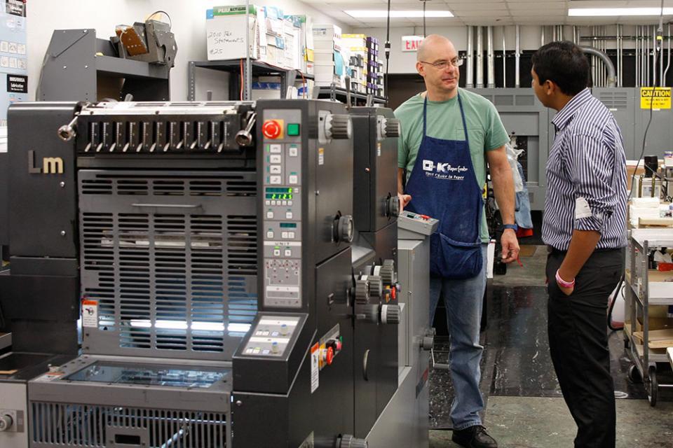 A gentleman teaching a student how to work a machine