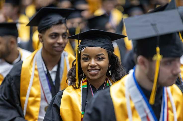 Graduating girl smiles at camera surrounded by fellow Garland High graduates.