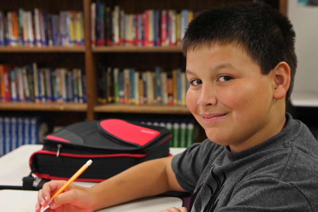 Boy looks up from paper to smile at camera