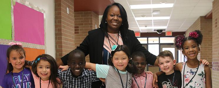A principal posing for a group photo with her elementary students.