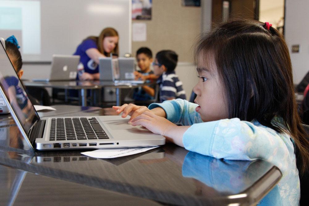 A young girl working on a laptop in class.