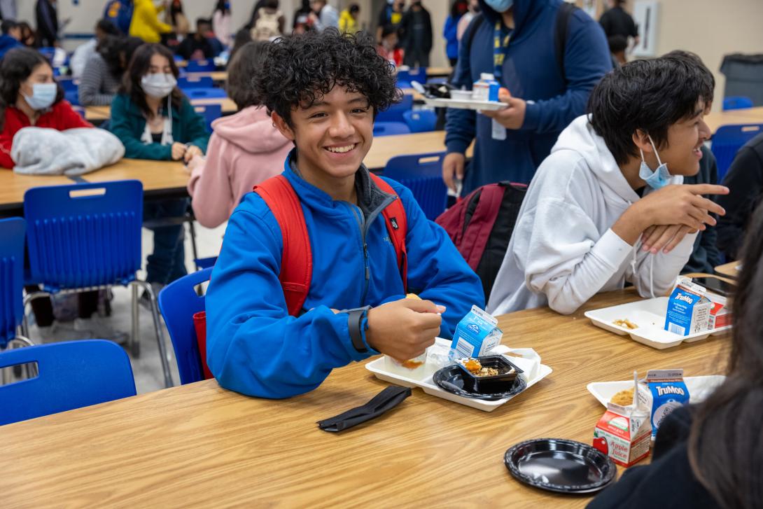 Smiling student eating breakfast in the cafeteria