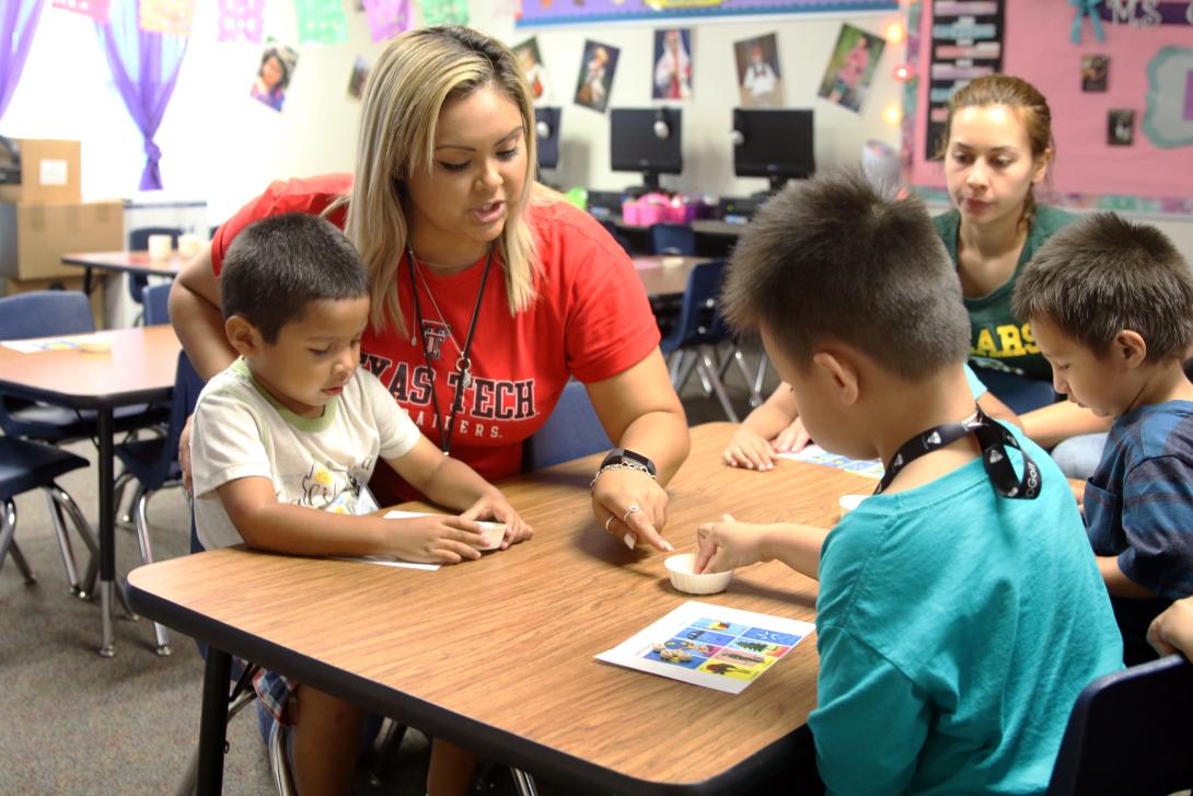 A teacher and aide helping a group of students