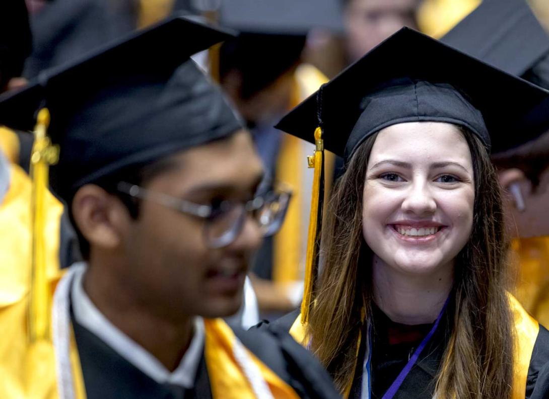 A student smiling while graduating among her peers