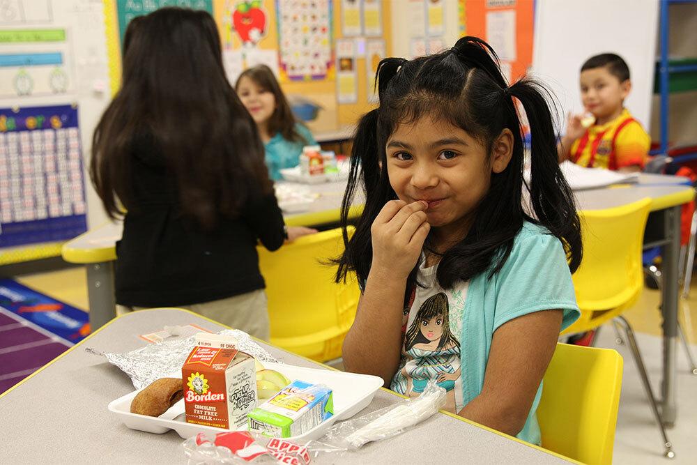 Smiling student eating breakfast in the classroom