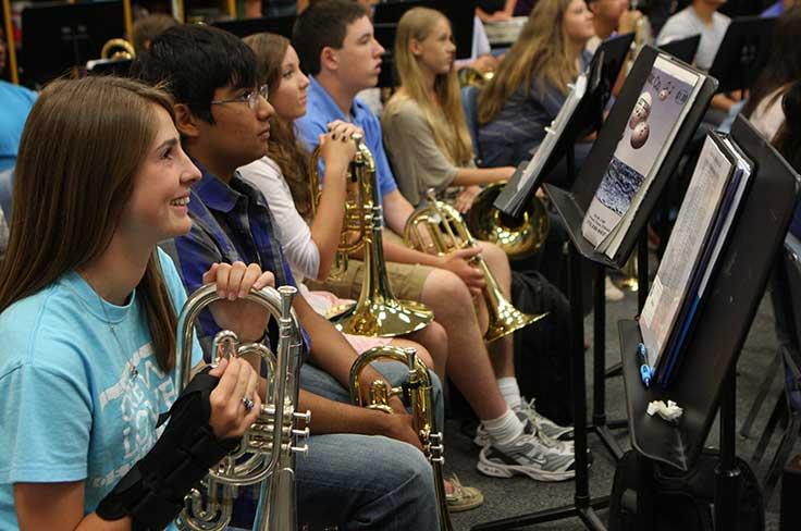 Band students holding instruments and looking at sheet music