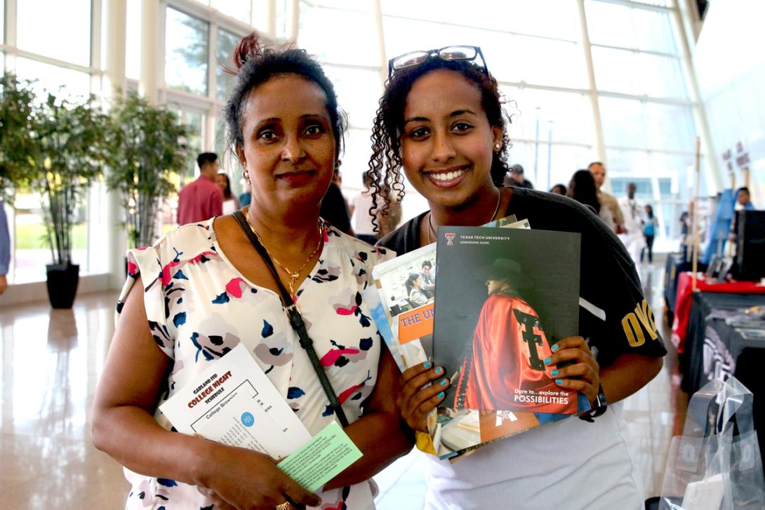 A mom and her daughter holding multiple college information packets