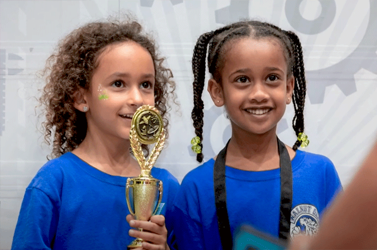 Two girls smiling holding their award at the STEAMposium