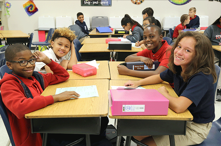 Smiling middle school kids at their desks