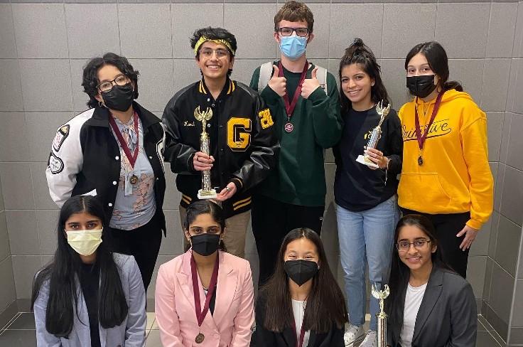 Students in speech and debate program holding trophy