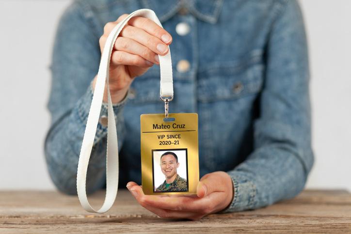 A person holding a VIP pass with an active military ID picture