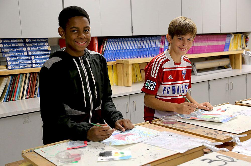 Two students smiling while working on an art assignment