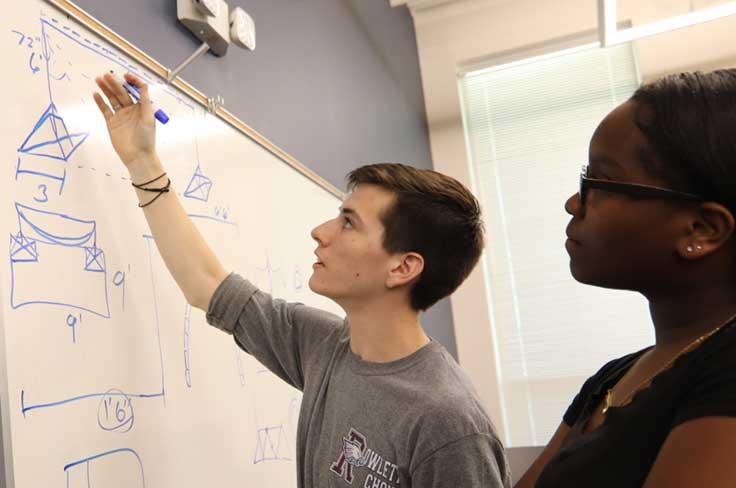 engineering students working on calculations at a whiteboard