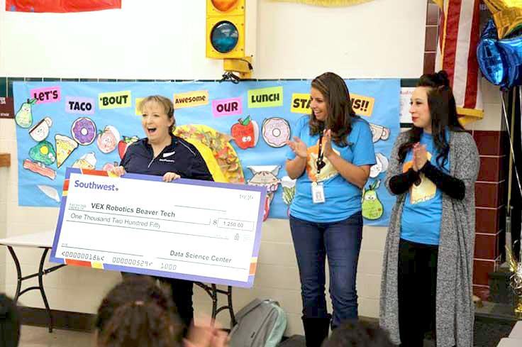 Teacher holding large check from business donation