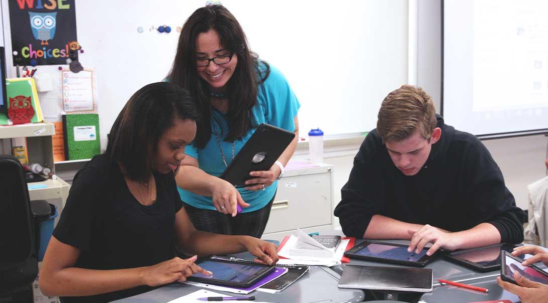 A teacher helping some students complete assignments on iPads.