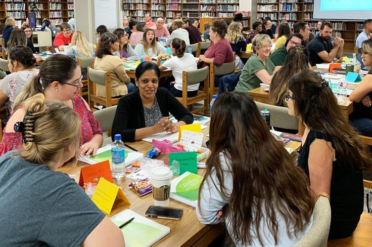 Teachers conferencing in a library at an onboarding event.