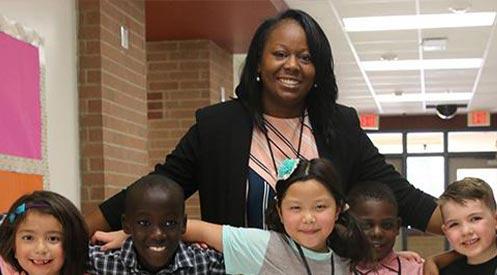 A principal posing with a group of smiling students.