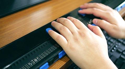 A blind child using a computer with a braille terminal.