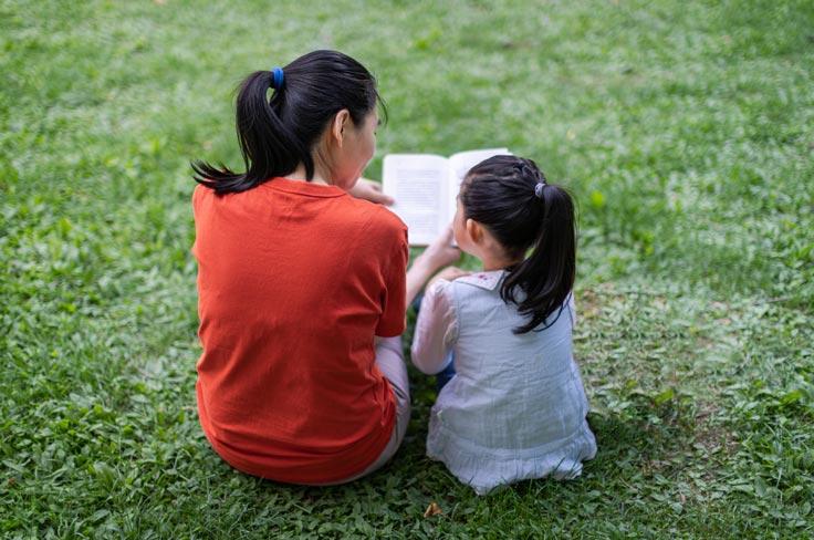 A mother and child reading outside.