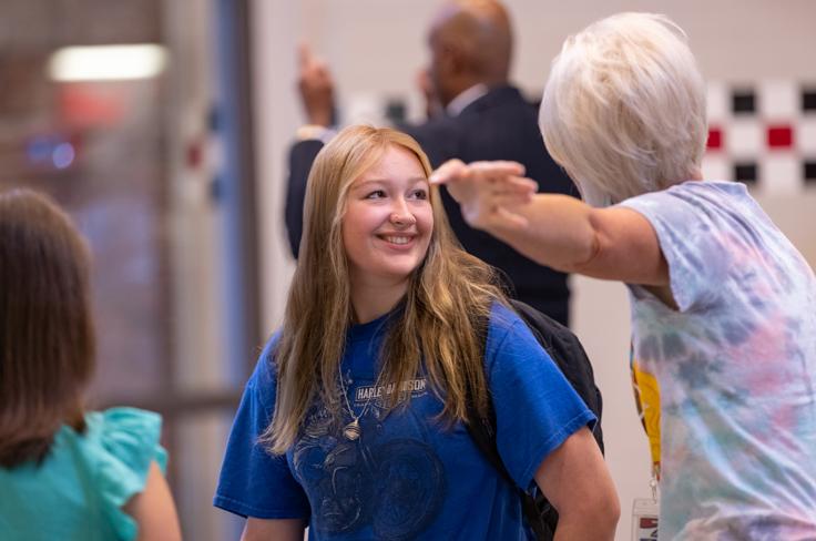 A high school student getting directions from a staff member on her first day.